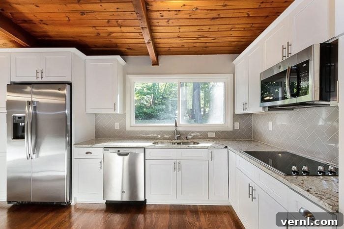 A dated kitchen with white and gray cabinets, a small island, and fluorescent lighting before renovation.