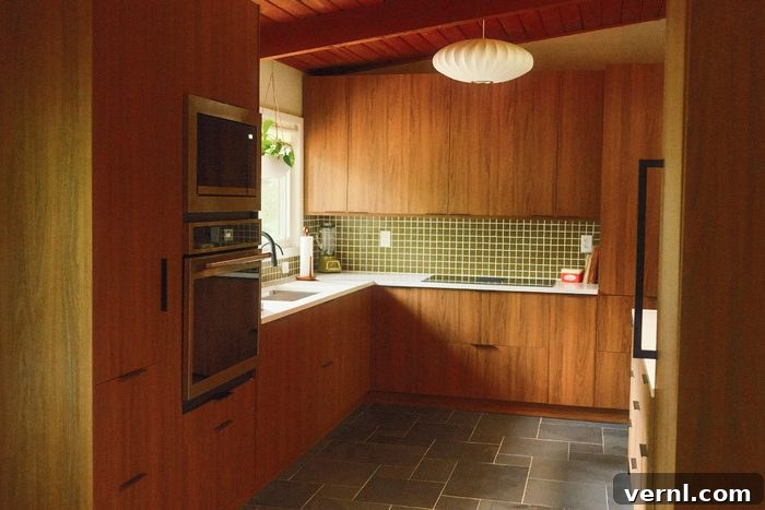 A renovated mid-century modern kitchen featuring green and brown tones, custom cabinetry, and period-appropriate fixtures.
