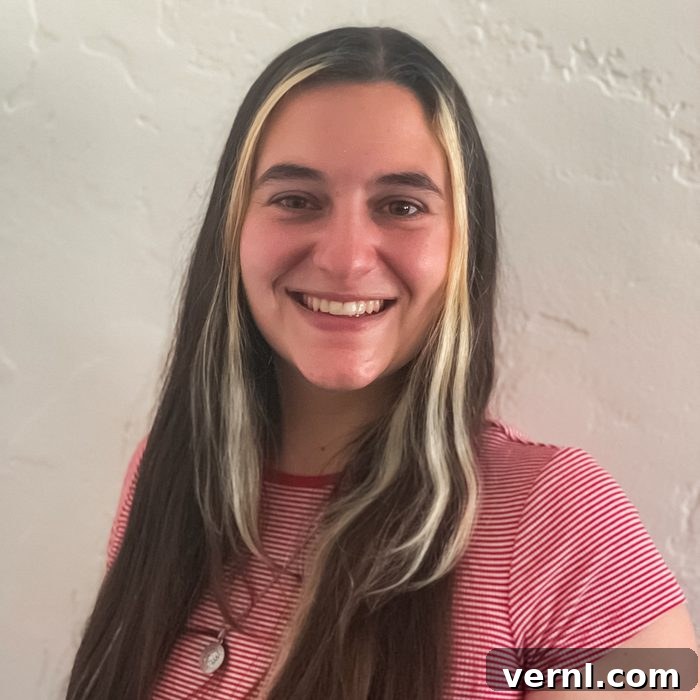 Family Handyman's Women Share Their DIY Insights 3 A person with long brown hair featuring blonde streaks smiles at the camera. They are wearing a red-and-white striped shirt and a necklace, standing in front of a textured white wall. Their expression is warm and inviting.