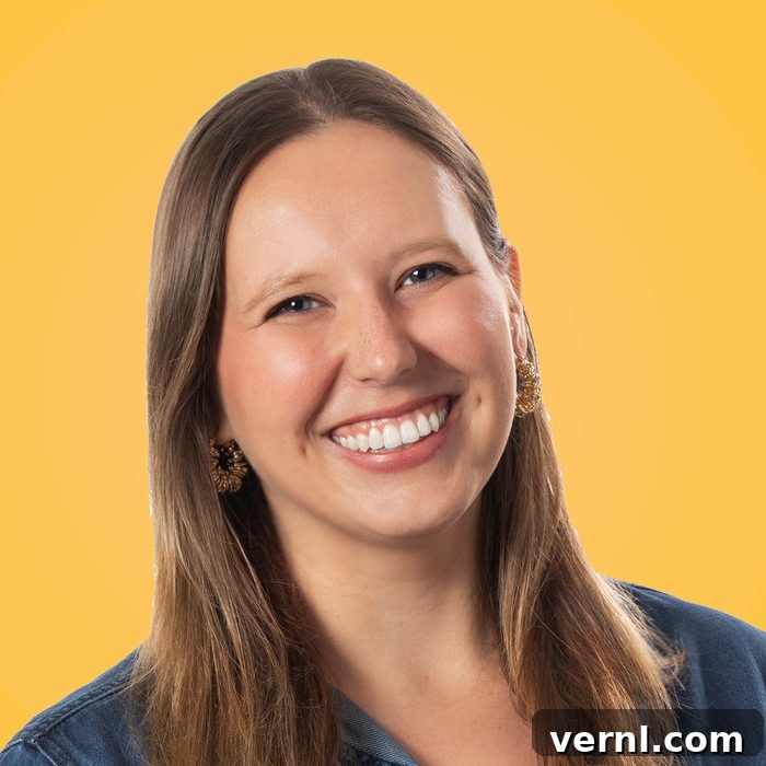 Family Handyman's Women Share Their DIY Insights 6 A woman with long brown hair smiles broadly, showing teeth. She is wearing a denim shirt and earrings, and stands in front of a bright yellow background. Her expression is joyful and approachable.
