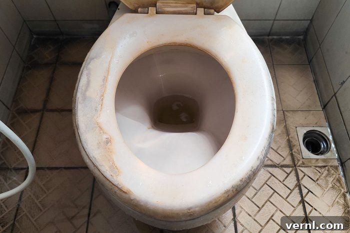 A top-down view of a used white ceramic toilet with visible yellow mineral stains and limescale buildup.