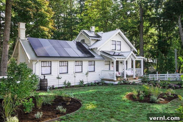 Pamela Anderson Restores Her Grandparents’ Home in Pamela’s Garden of Eden 2 A white house with solar panels on the roof sits among tall trees, surrounded by a green lawn, landscaped garden beds, and a white picket fence.