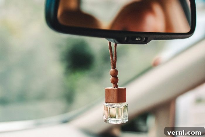 Do Car Air Fresheners Harm Your Health? 2 Car air parfume on the frontal mirror of the car with blurred green background outside the window