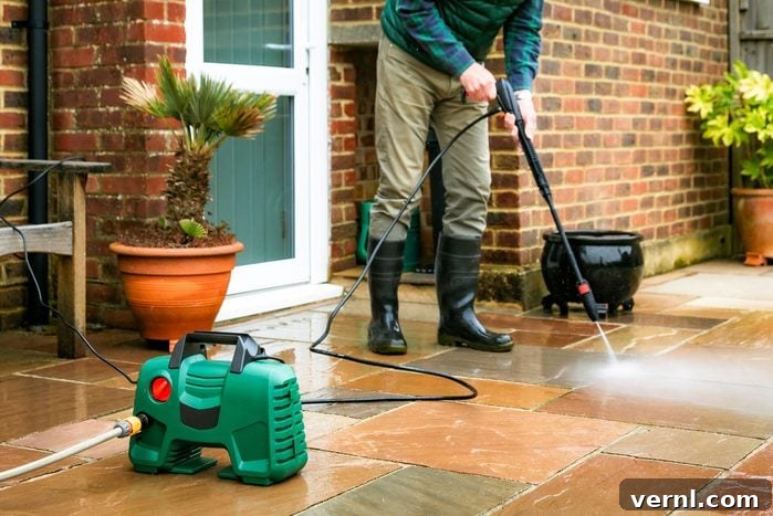 Senior man cleaning patio tiles using pressure washer