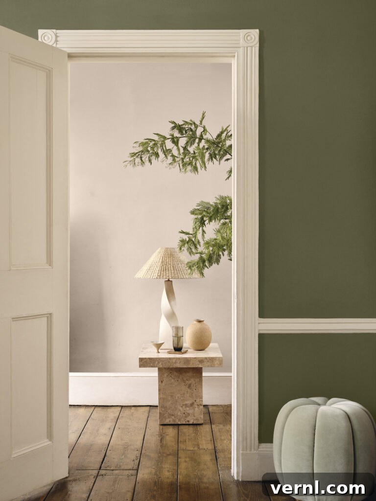 8 Interior Design Trends and Terms to Know in 2025 4 Looking through a doorway from a sage green hallway painted in low VOC eco-friendly paint into a white living space.