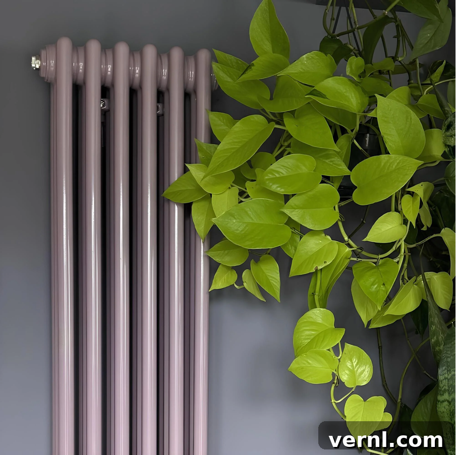 Unique Radiator Designs to Transform Your Home Renovation 4 A vertical column radiator against a blue wall next to a plant.
