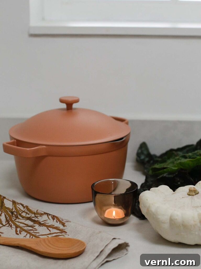 Our Place Perfect Pot with candle, wooden spoon, and autumn decor on a kitchen countertop.
