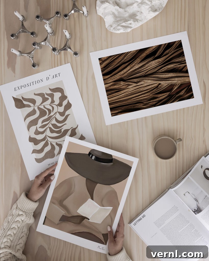 A selection of art prints on a wooden tabletop representing Mocha Mousse, the Pantone Colour of the Year for 2025.