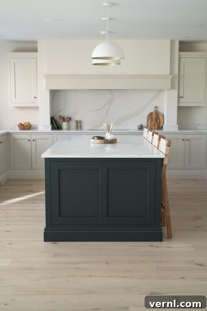 Elegant shaker-style kitchen island featuring dark green cabinetry, a marble top, and cozy wood bar stools in a light-filled space.