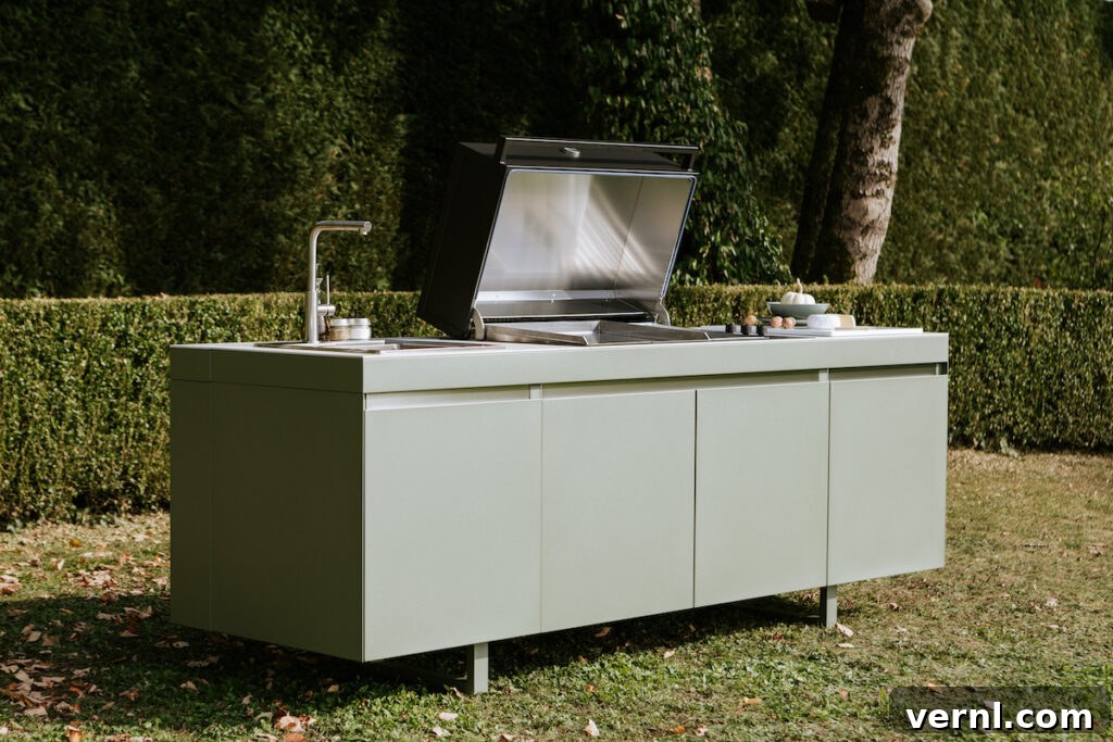 Sleek green outdoor kitchen island with built-in grill, sink, and spacious storage, set in a lush garden for stylish alfresco cooking.