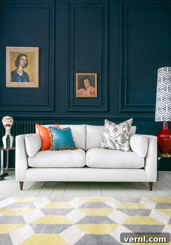 Why Odd Numbers Improve Design: Styling in 3s and 5s 3 A modern living room with dark blue panelled walls, a white sofa, colorful accent pillows, vintage framed paintings, and a geometric yellow and grey rug.