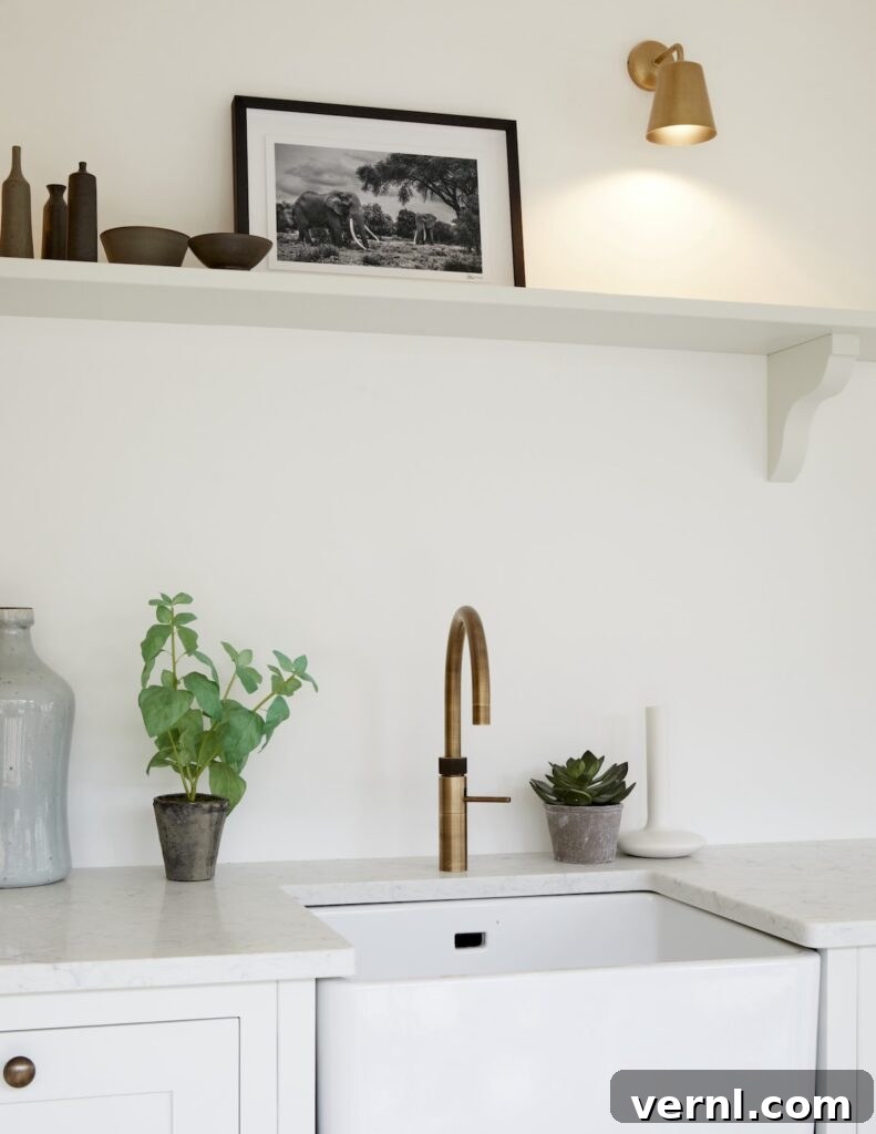 10 Clever Small Kitchen Ideas to Maximize Space and Function 3 A sleek small kitchen featuring a brass faucet, white countertops, open shelving with minimalist decor, and potted plants for a modern touch.
