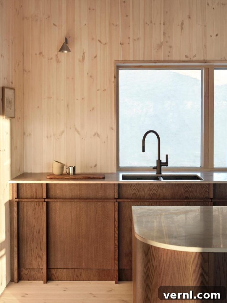Modern Mountain Cabin: A Stunning Design Retreat 2 Minimalist kitchen featuring warm wood kitchen cabinets and a sleek black faucet by a large window.