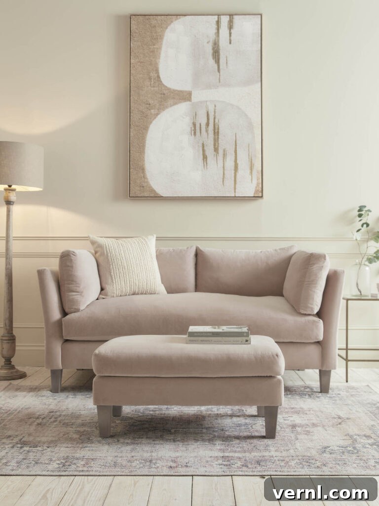 6 Colors That Complement Magnolia Walls for a Timeless Look 9 Soft and neutral living room featuring a blush pink sofa, matching ottoman, magnolia-toned walls, and abstract artwork.
