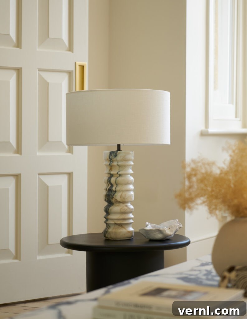 Refresh a Room That Feels Off Using Only Items You Already Own 4 A table lamp with a drum shade and marble base in an elegant room.