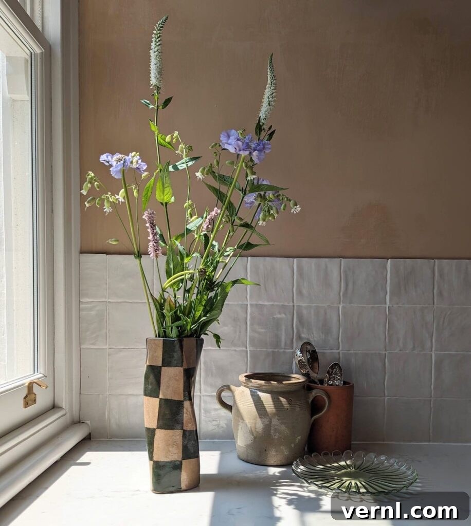 Refresh a Room That Feels Off Using Only Items You Already Own 8 A check twist vase filled with flowers standing next to a window.