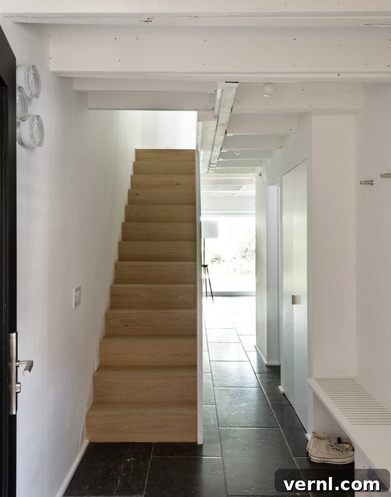 Brooklyn Row House Renovation for Modern Family Living 11
Minimalist hallway with light wood staircase and black slate tile flooring.