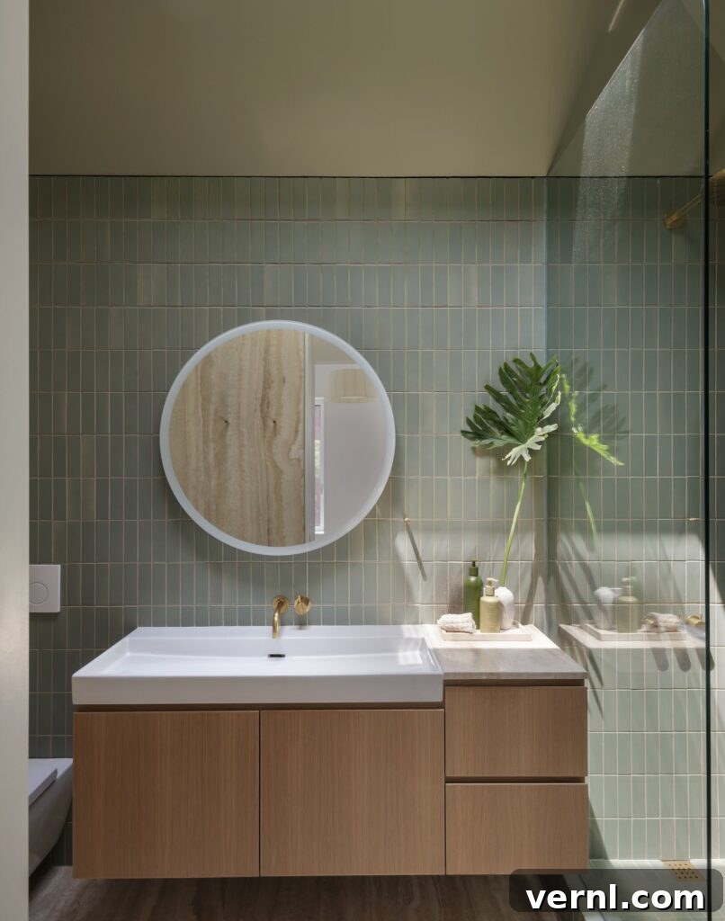 Brooklyn Row House Renovation for Modern Family Living 7
Green tiled bathroom with wood vanity, round mirror, and gold fixtures.