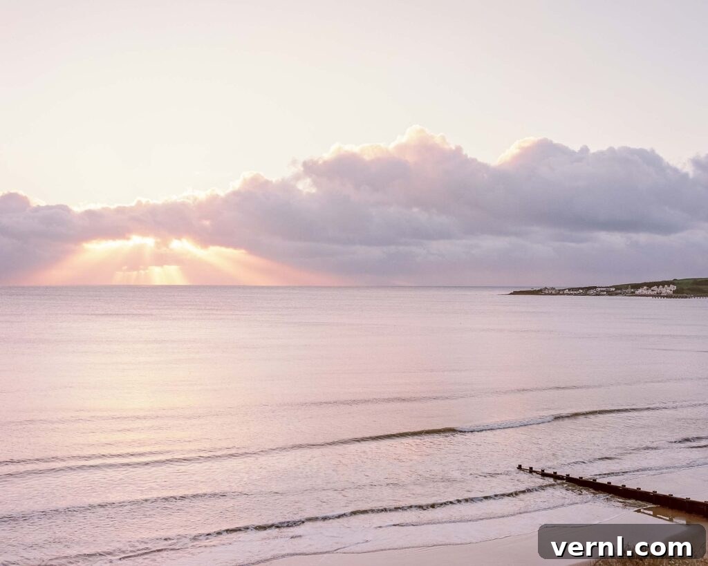Inside a Dorset Beach House: Modern Coastal Living 12 Sunrise over calm sea with light rays through clouds.
