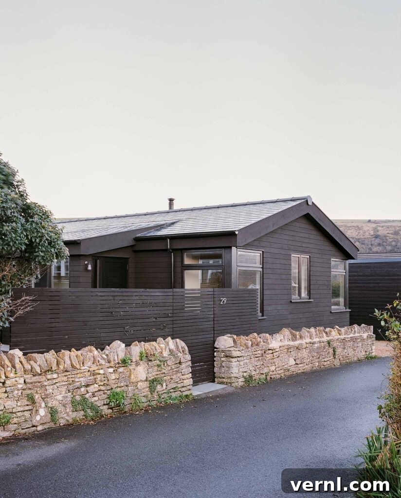 Inside a Dorset Beach House: Modern Coastal Living 3 Modern black wood cabin with stone wall and pitched roof.