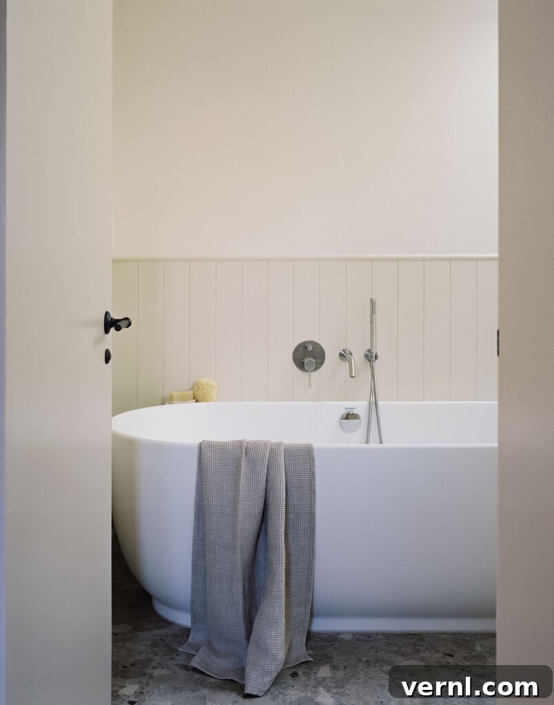 Inside a Dorset Beach House: Modern Coastal Living 9 Freestanding white bathtub with towel and wall-mounted fixtures.
