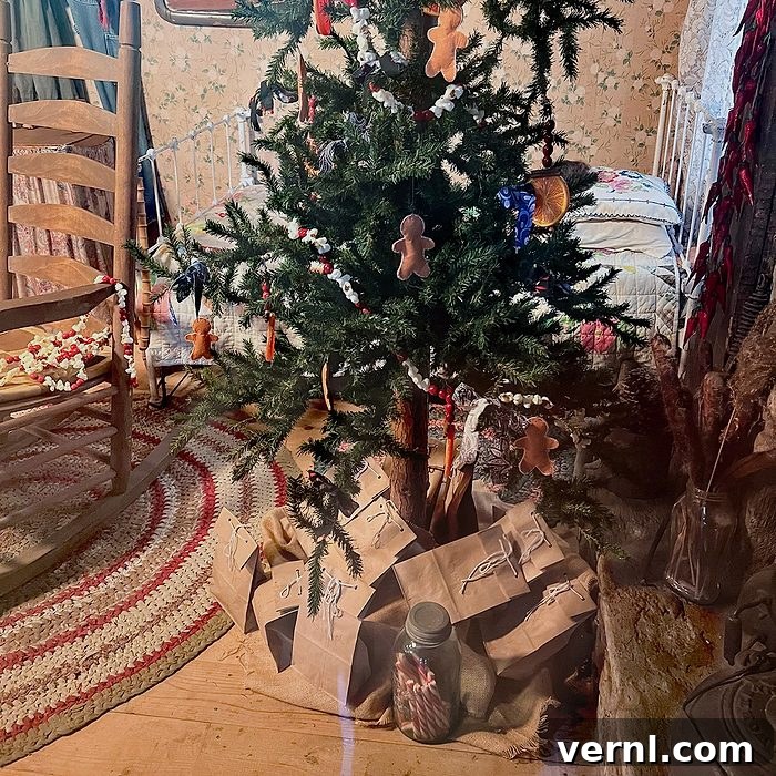 A small Christmas tree decorated with gingerbread ornaments stands on a wooden floor, surrounded by brown paper-wrapped packages and a jar. A wooden chair and braided rug are nearby in a cozy, rustic room.