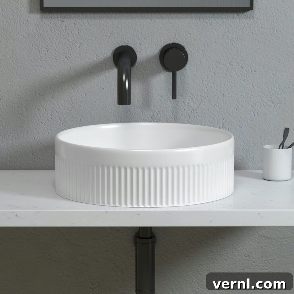 A fluted round countertop basin on a marble worktop with black taps.